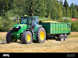 thumbnail of john-deere-6155r-farm-tractor-and-kire-agricultural-trailer-full-of-harvested-wheat-in-field-on-a-beautiful-day-salo-finland-july-25-2021-2GA0BDR.jpg
